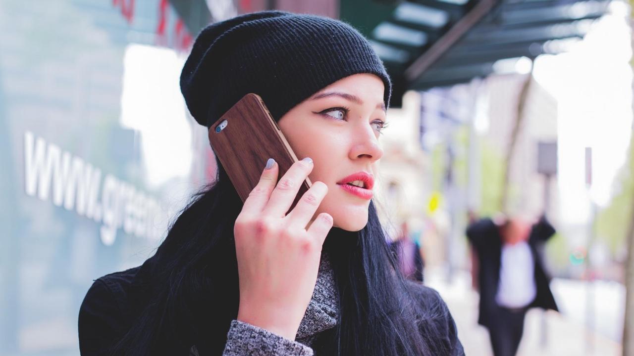 Eine junge Frau mit Wollmütze telefoniert mit ihrem Smartphone. Eine junge Frau mit Wollmütze telefoniert mit ihrem Smartphone.