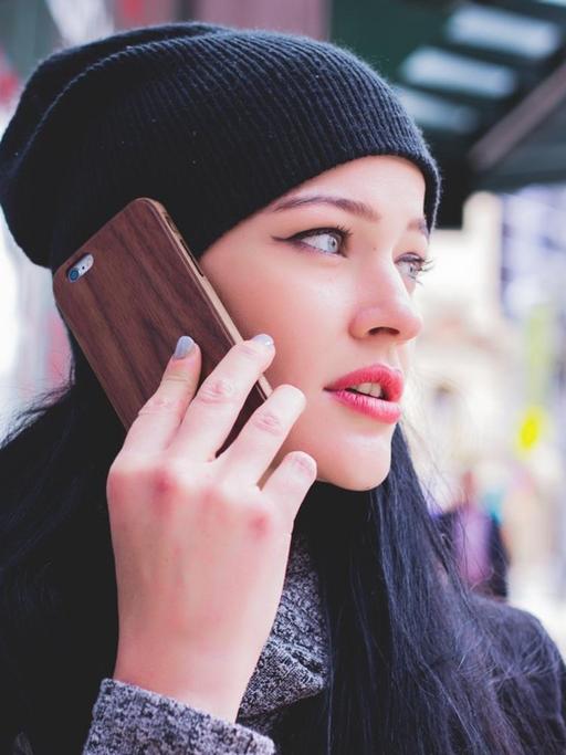 Eine junge Frau mit Wollmütze telefoniert mit ihrem Smartphone.