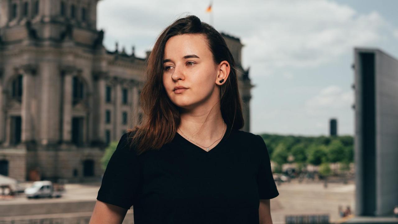 Noreen Thiel in schwarzem T-Shirt vor dem Reichstagsgebäude im Hintergrund. Noreen Thiel in schwarzem T-Shirt vor dem Reichstagsgebäude im Hintergrund.