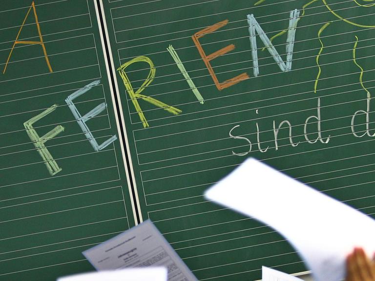Schüler einer ersten Klasse halten am 29.07.2014 in einer Grundschule in Kaufbeuren (Bayern) ihre Zeugnisse vor einer Tafel mit der Aufschrift "Hurra Ferien sind da". Für rund 1,54 Millionen Schüler in Bayern beginnen die Sommerferien.