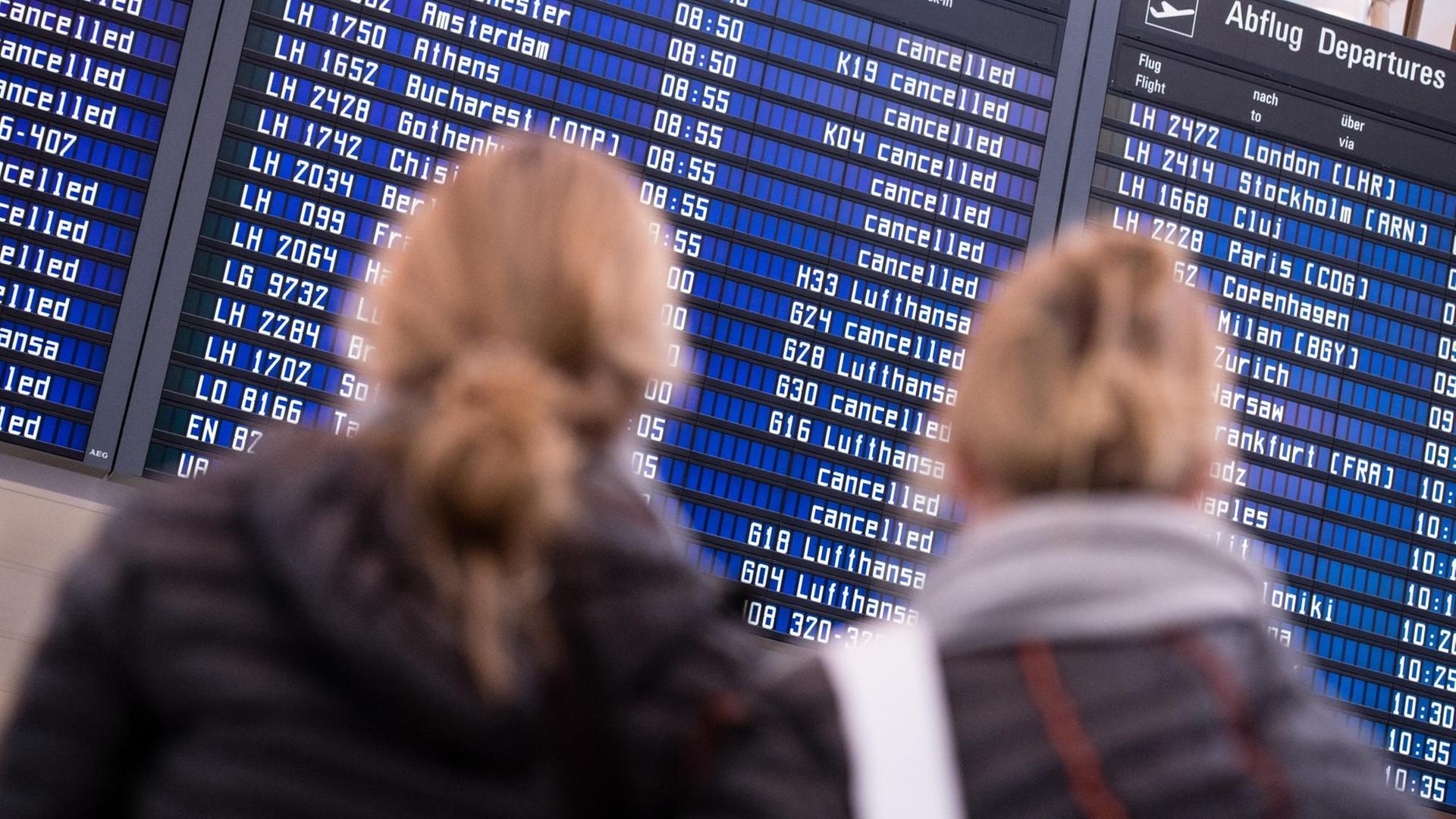 Zwei Frauen blicken am 23.11.2016 auf dem Flughafen in München (Bayern) auf Anzeigetafeln, auf denen zahlreiche annullierte Flüge der Fluggesellschaft Lufthansa ausgewiesen sind. Die Lufthansa-Piloten sind in der Nacht zum 23.11.2016 in einen zweitägigen Streik getreten.