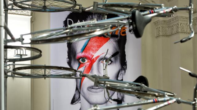 Das Plakat zur Ausstellung «David Bowie» hängt am 18.05.2014 im Vestibül des Martin-Gropius-Bau in Berlin hinter einer Fahrrad-Installation des chinesischen Künstlers Ai Weiwei.