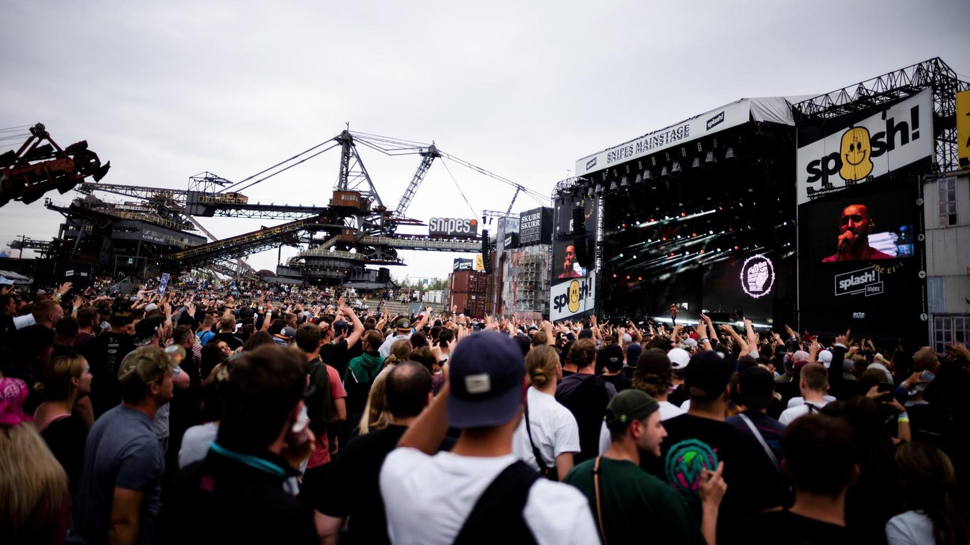 Blick auf eine Bühne des Splash-Festivals. Eine Menge an Menschen steht davor, im Hintergrund ist ein Tagebaubagger zu sehen. Blick auf eine Bühne des Splash-Festivals. Eine Menge an Menschen steht davor, im Hintergrund ist ein Tagebaubagger zu sehen.