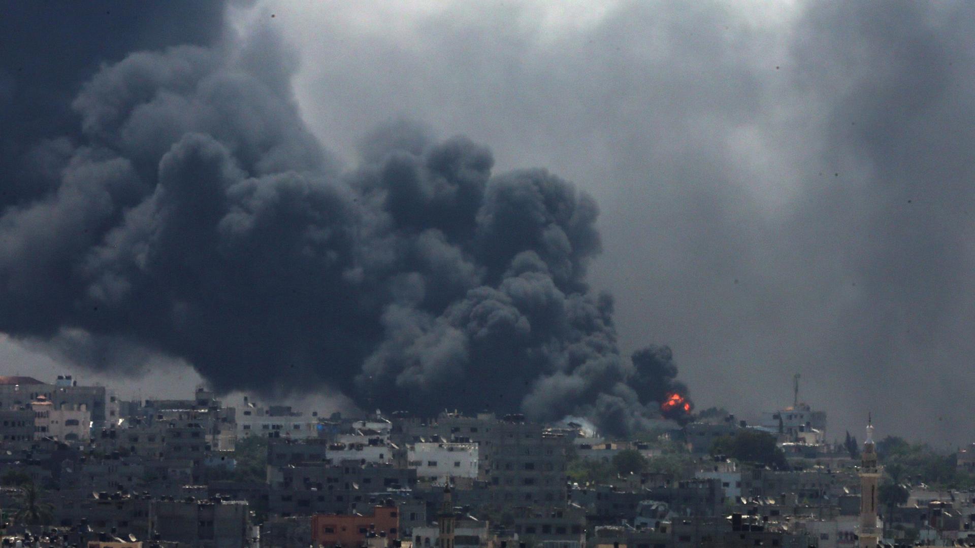 Panorama-Ansicht von Al Shejaeiya: Ein Haus auf einem Hügel brennt, von dort aus steigt eine dichte Wolke mit schwarzem Rauch über die Stadt auf. Panorama-Ansicht von Al Shejaeiya: Ein Haus auf einem Hügel brennt, von dort aus steigt eine dichte Wolke mit schwarzem Rauch über die Stadt auf.