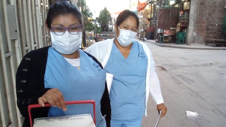 Thelma Soria und eine Kollegin mit Atemschutzmasken und einer Kühlbox in der Hand. Thelma Soria und eine Kollegin mit Atemschutzmasken und einer Kühlbox in der Hand.