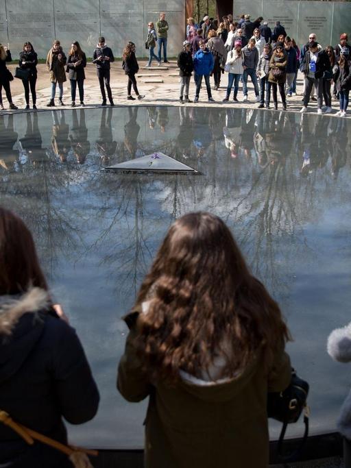 Mehrere Schüler stehen in Berlin an der Gedenkstätte für die in der Zeit des Nationalsozialismus ermordeten Sinti und Roma. 