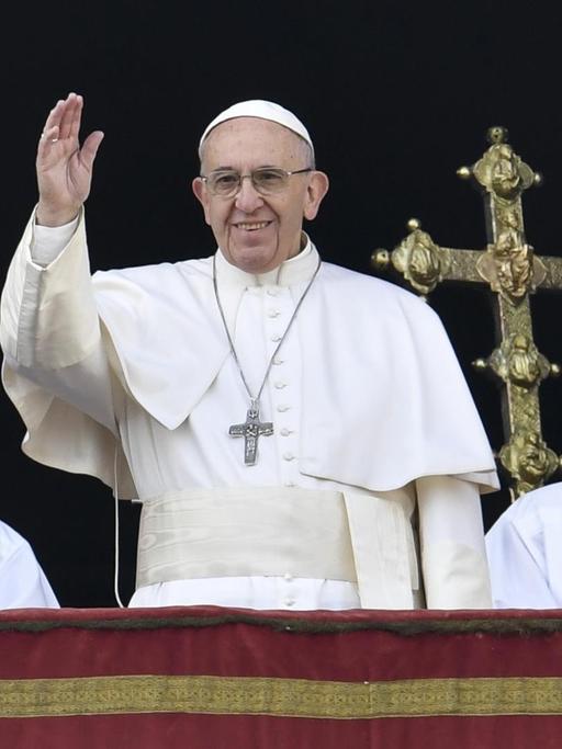 Papst Franziskus und zwei weitere Männer stehen auf dem Balkon des Petersdoms.