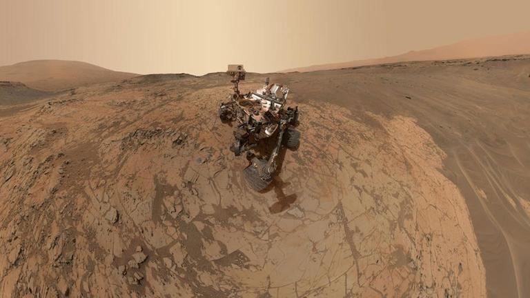 In der Marslandschaft steht ein futuristisch anmutendes Gefährt. In der Marslandschaft steht ein futuristisch anmutendes Gefährt.