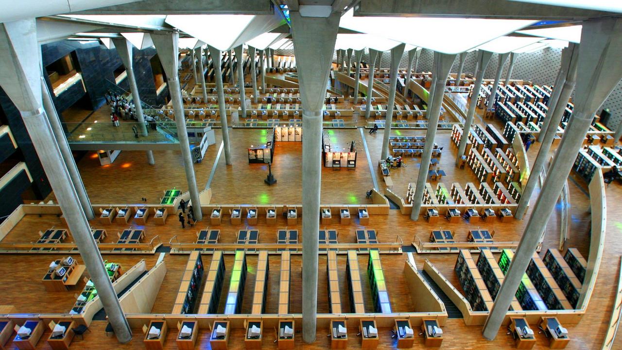 Blick in den Lesesaal der Bibliotheca Alexandrina. Darin zu sehen sind Reihen von Tischen zum Teil mit Computern ausgestattet. Blick in den Lesesaal der Bibliotheca Alexandrina. Darin zu sehen sind Reihen von Tischen zum Teil mit Computern ausgestattet.