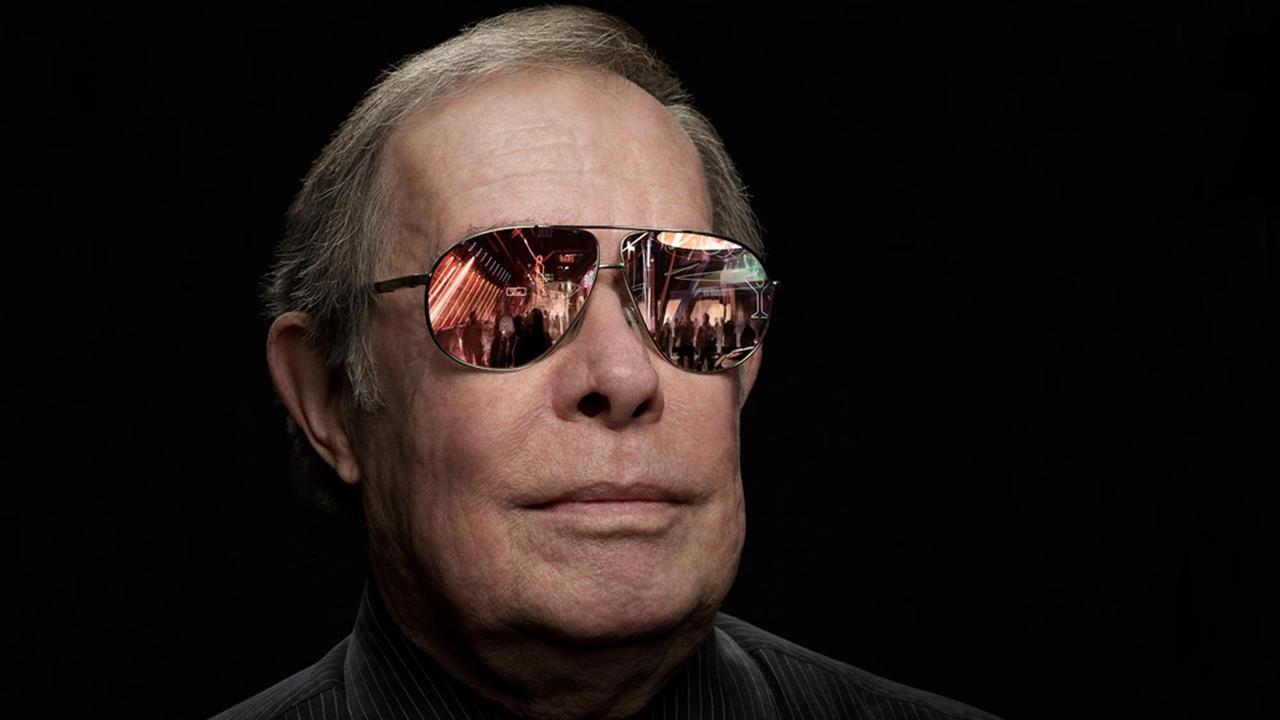 Portrait des Designers Syd Mead mit einer Sonnenbrille, in der sich vermeintlich eine futuristische Stadtszenerie spiegelt. Portrait des Designers Syd Mead mit einer Sonnenbrille, in der sich vermeintlich eine futuristische Stadtszenerie spiegelt.