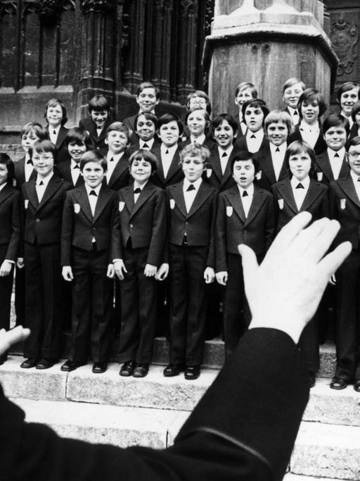 Der Chorleiter Monsignore Georg Ratzinger dirigiert die Domspatzen vor dem Dom in Regensburg am 09.04.1976. Der Regenburger Domchor, "Domspatzen" im Volksmund genannt, beging 1976 mit dem 700-jährigen Jubiläum des Regenburger Doms Sankt Peter sein 1000-jähriges Bestehen. Die Geschichte des Chores geht auf die Anfänge des Bistums Regensburg im achten Jahrhundert zurück. Seit 1964 singt er unter der Leitung von Domkapellmeister Monsignore Georg Ratzinger.