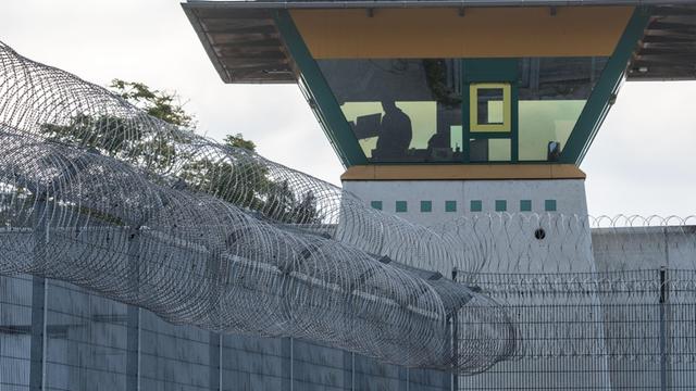 Ein Wachturm in einer Justizvollzugsanstalt hinter einem Zaun mit Stacheldraht.