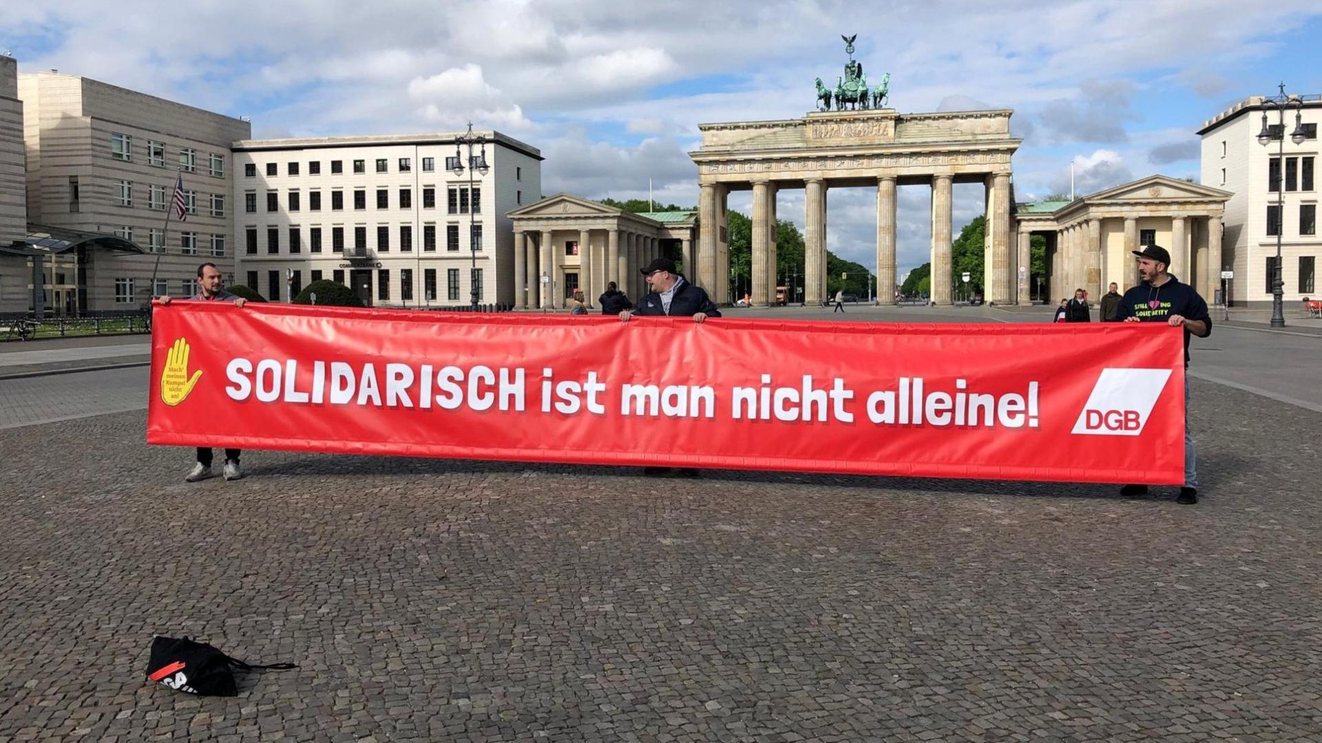 Demonstranten tragen ein Banner mit der Aufschrift "Solidarisch ist man nicht alleine" vom Deutschen Gewerkschaftbund vor dem Brandenburger Tor in Berlin Demonstranten tragen ein Banner mit der Aufschrift "Solidarisch ist man nicht alleine" vom Deutschen Gewerkschaftbund vor dem Brandenburger Tor in Berlin