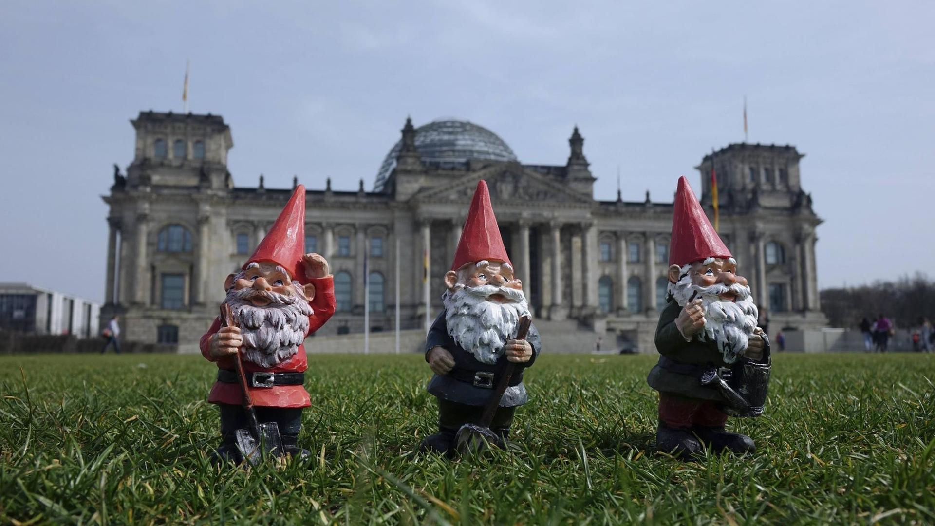 Drei Gartenzwerge stehen auf der Wiese vor dem Reichstag in Berlin. Drei Gartenzwerge stehen auf der Wiese vor dem Reichstag in Berlin.