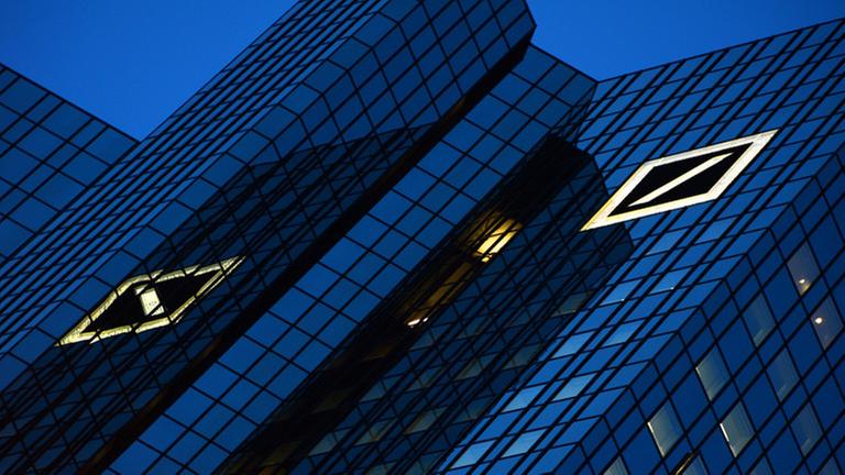 Das Logo der Deutschen Bank leuchtet am 08.01.2014 im Abendlicht auf der Fassade des größten deutschen Geldinstituts in Frankfurt am Main (Hessen). Foto: Arne Dedert/dpa Das Logo der Deutschen Bank leuchtet am 08.01.2014 im Abendlicht auf der Fassade des größten deutschen Geldinstituts in Frankfurt am Main (Hessen). Foto: Arne Dedert/dpa