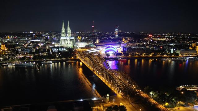 Eine Luftaufnahme zeigt das Panorama von Köln abends - mit Dom und Rhein.