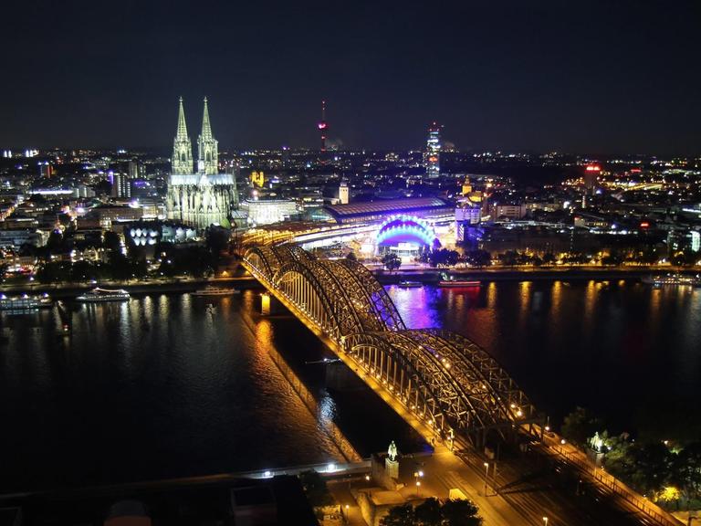 Eine Luftaufnahme zeigt das Panorama von Köln abends - mit Dom und Rhein.