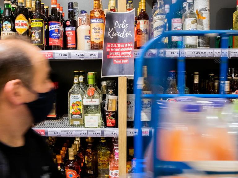 Ein Mitarbeiter schiebt in einem Supermarkt in Berlin-Schöneberg in der Getränkeabteilung kurz vor Beginn des für Silvester geltenden Verkaufsverbots von alkoholischen Getränken vor einem Hinweisschild einen Wagen.