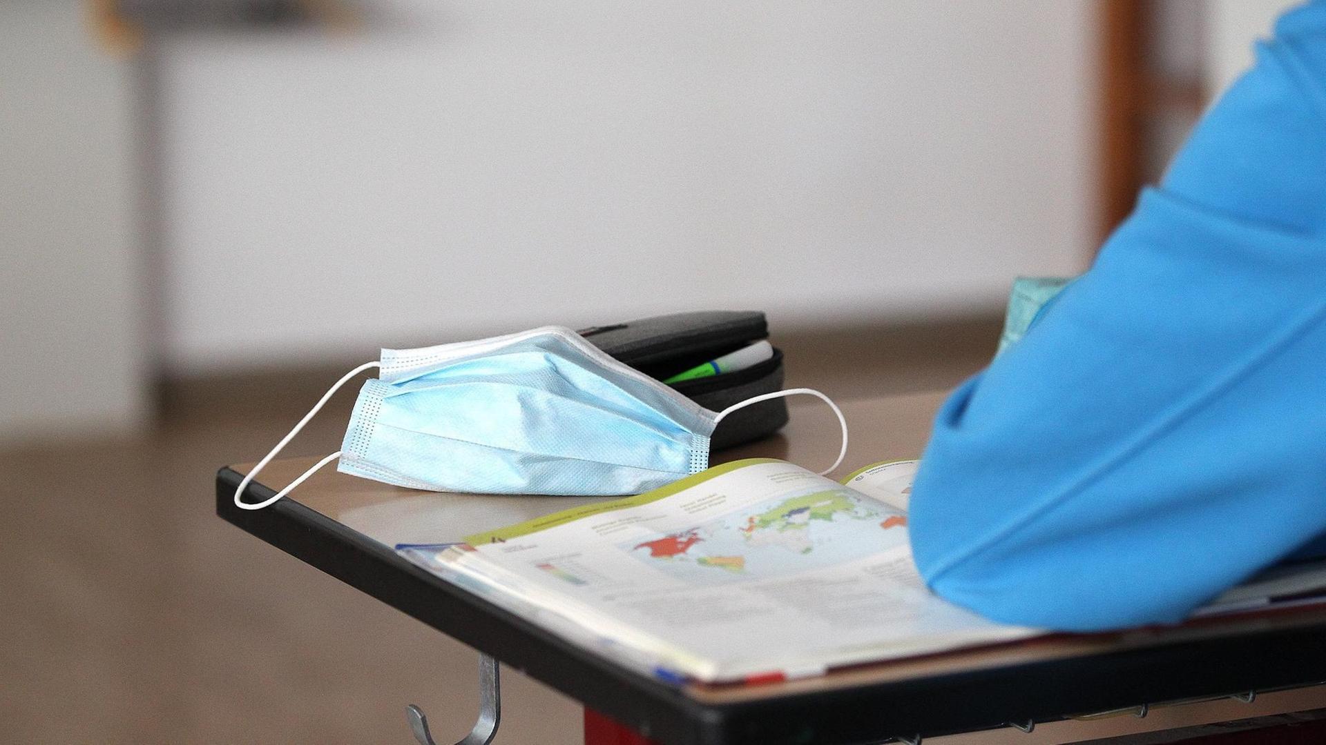 Eine OP-Maske liegt auf einem Schultisch in einer Klasse. Eine OP-Maske liegt auf einem Schultisch in einer Klasse.