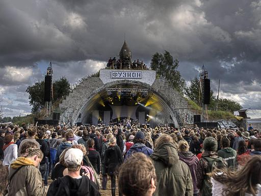 Über der Hauptbühne des Fusion Festivals im mecklenburgischen Lärz sind dunkle Wolken zu sehen. Vor der Bühnen stehen Hunderte Menschen.