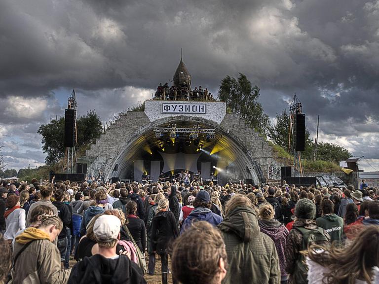 Über der Hauptbühne des Fusion Festivals im mecklenburgischen Lärz sind dunkle Wolken zu sehen. Vor der Bühnen stehen Hunderte Menschen.