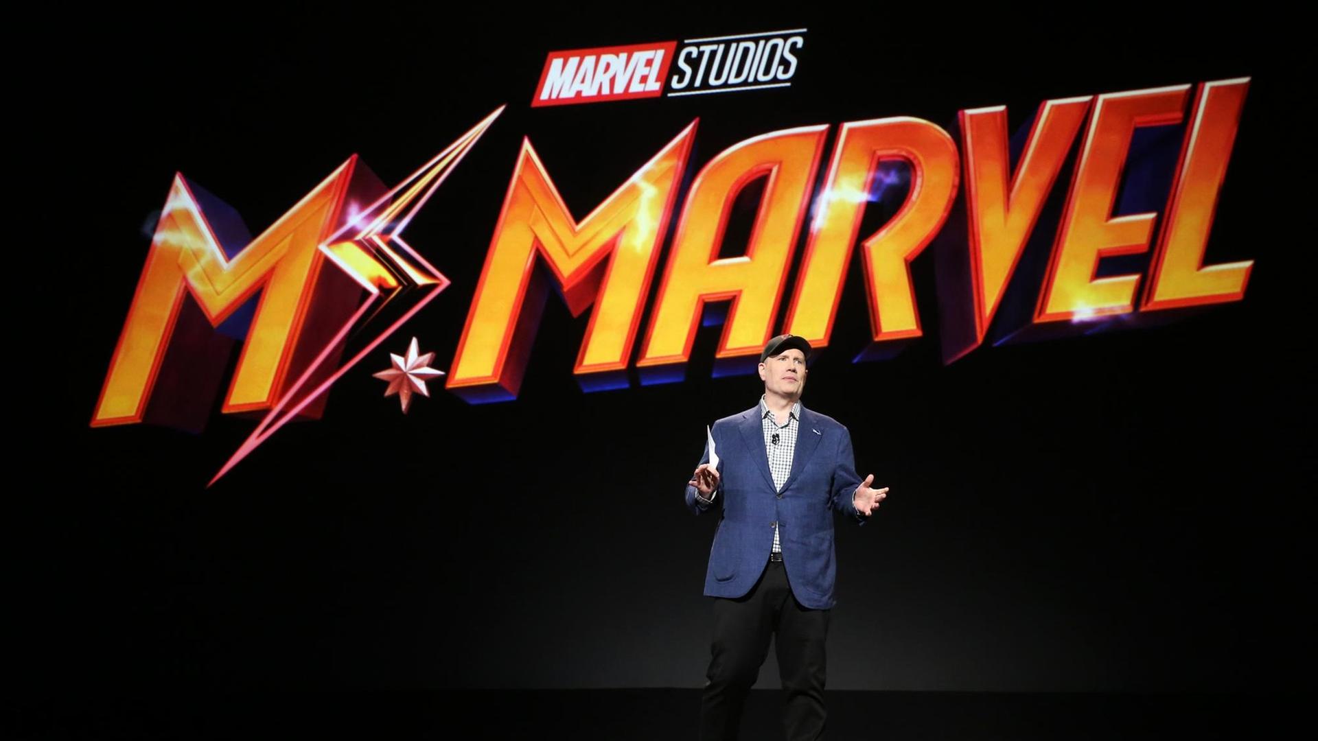 Der Präsident der Marvel Studios, Kevin Feige, auf einer Bühne bei einer Präsentation. Hinter ihm steht in grosser orangener Schrift: Mr. Marvel. Der Präsident der Marvel Studios, Kevin Feige, auf einer Bühne bei einer Präsentation. Hinter ihm steht in grosser orangener Schrift: Mr. Marvel.