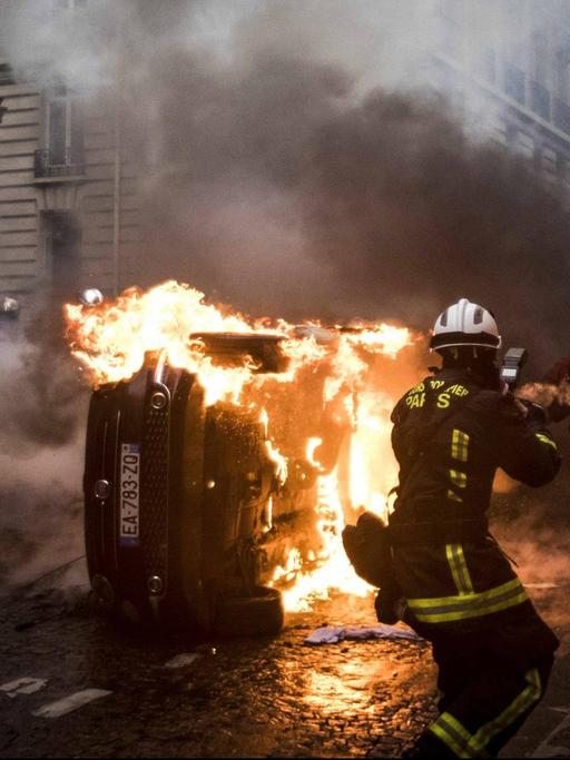Feuerwehrleute löschen ein brennendes Auto in Paris.