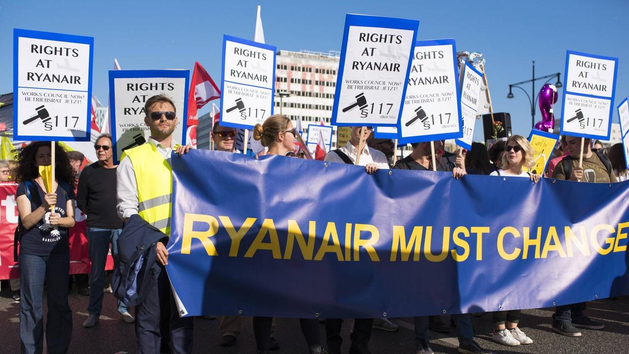 Demonstranten tragen ein blaues Transparent mit der Aufschrift "Ryanair must change"
