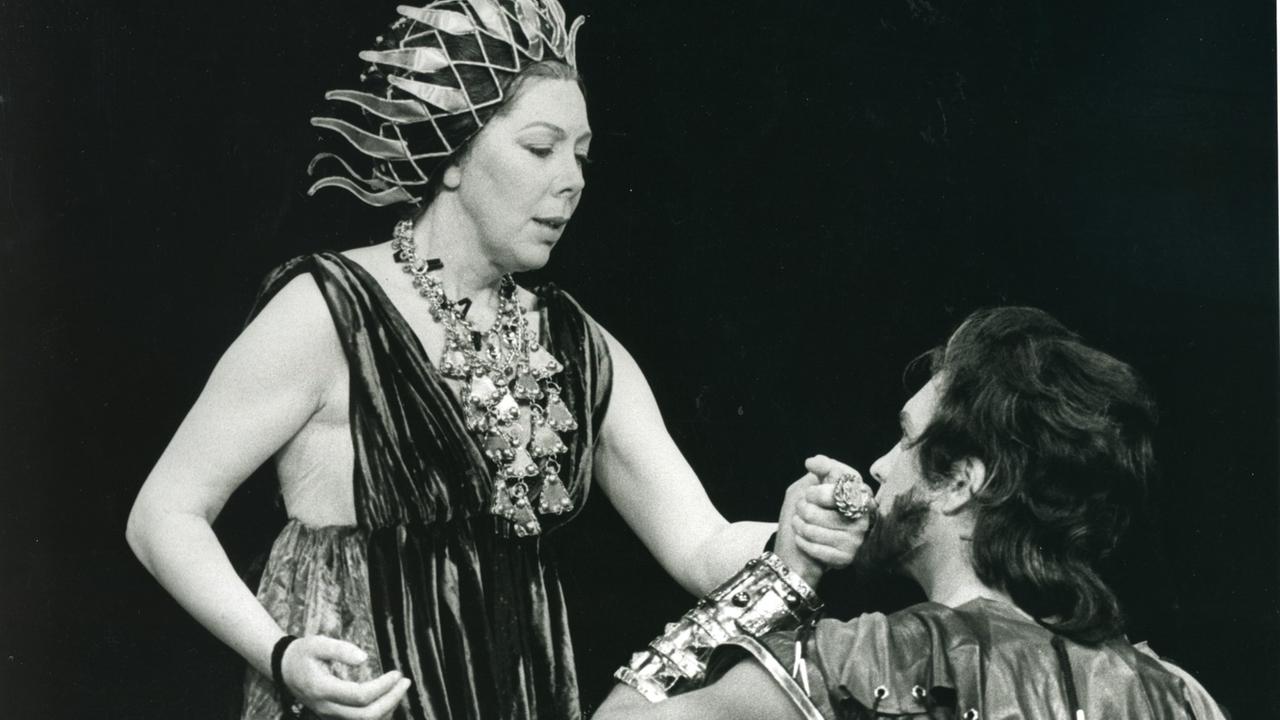 Schwarz-weiß Foto, links im Bild die Sängerin als Dido in einem antiken Kostüm mit Flammen artigen Haarschmuck, rechts knieend der Sänger mit längerem Haar und Bart und Goldschmuck am Arm seine linke Hand hält ihre rechte Hand