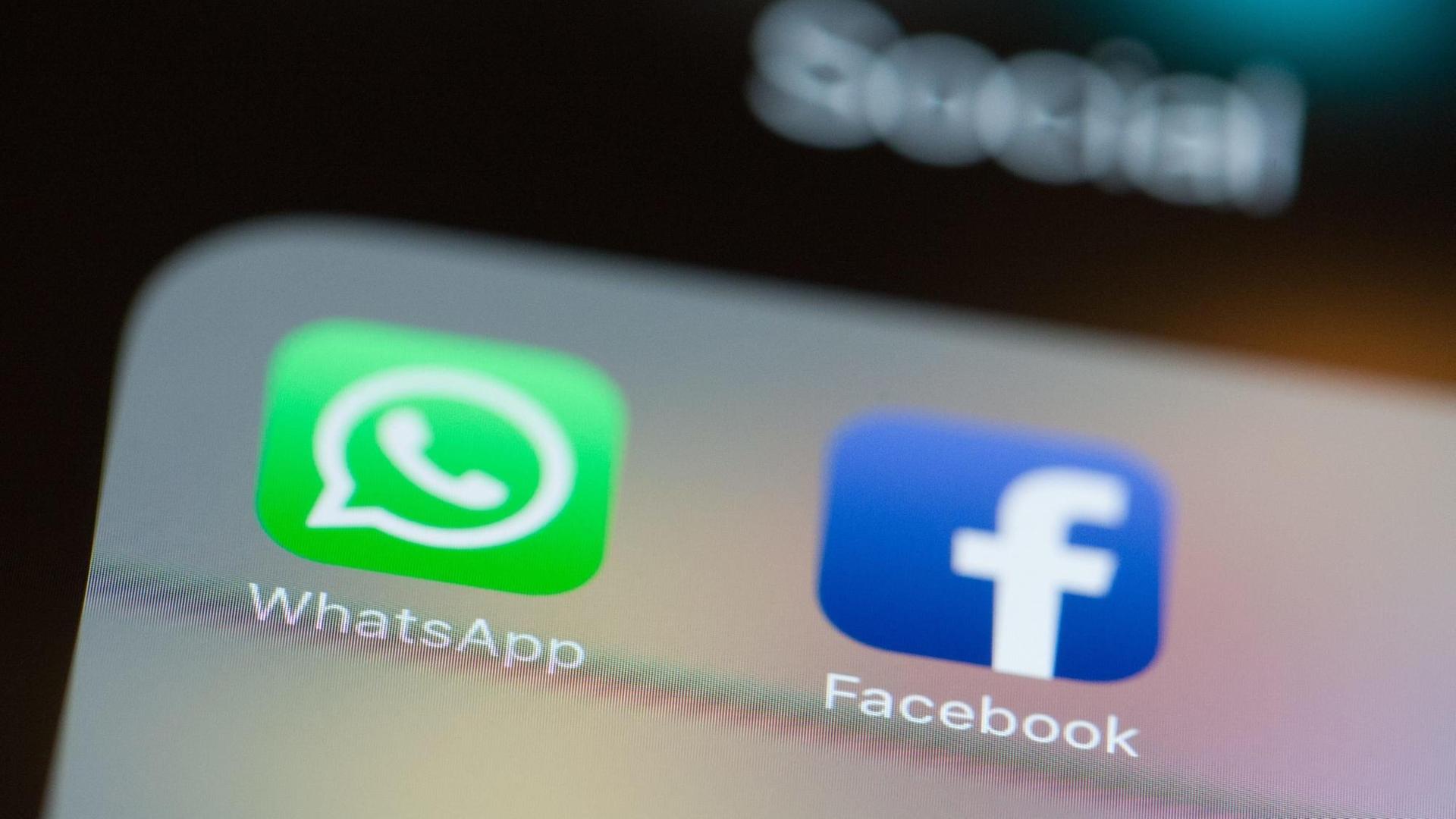 Die Logos von WhatsApp und Facebook leuchten auf einem Smartphone-Bildschirm. Die Logos von WhatsApp und Facebook leuchten auf einem Smartphone-Bildschirm.