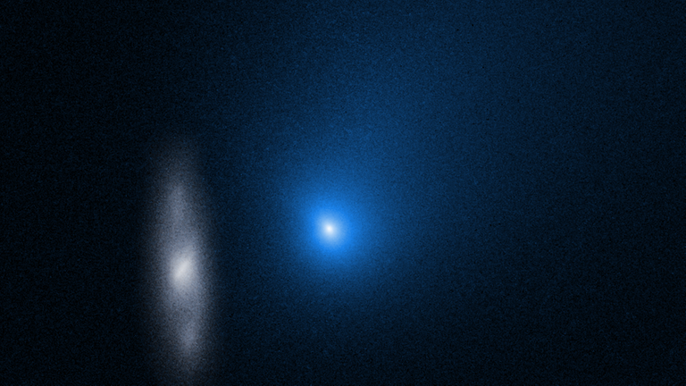 Ein Aufnahme des Hubble-Weltraumteleskops zeigt den interstellaren Kometen 2I/Borisov ungefähr an seinem sonnennächsten Punkt. Im Hintergrund ist die weit entfernte Sprialgalaxie 2MASX J10500165-0152029 zu erkennen. Der Schweif des Kometen zeigt zum rechten Rand des Bildes.