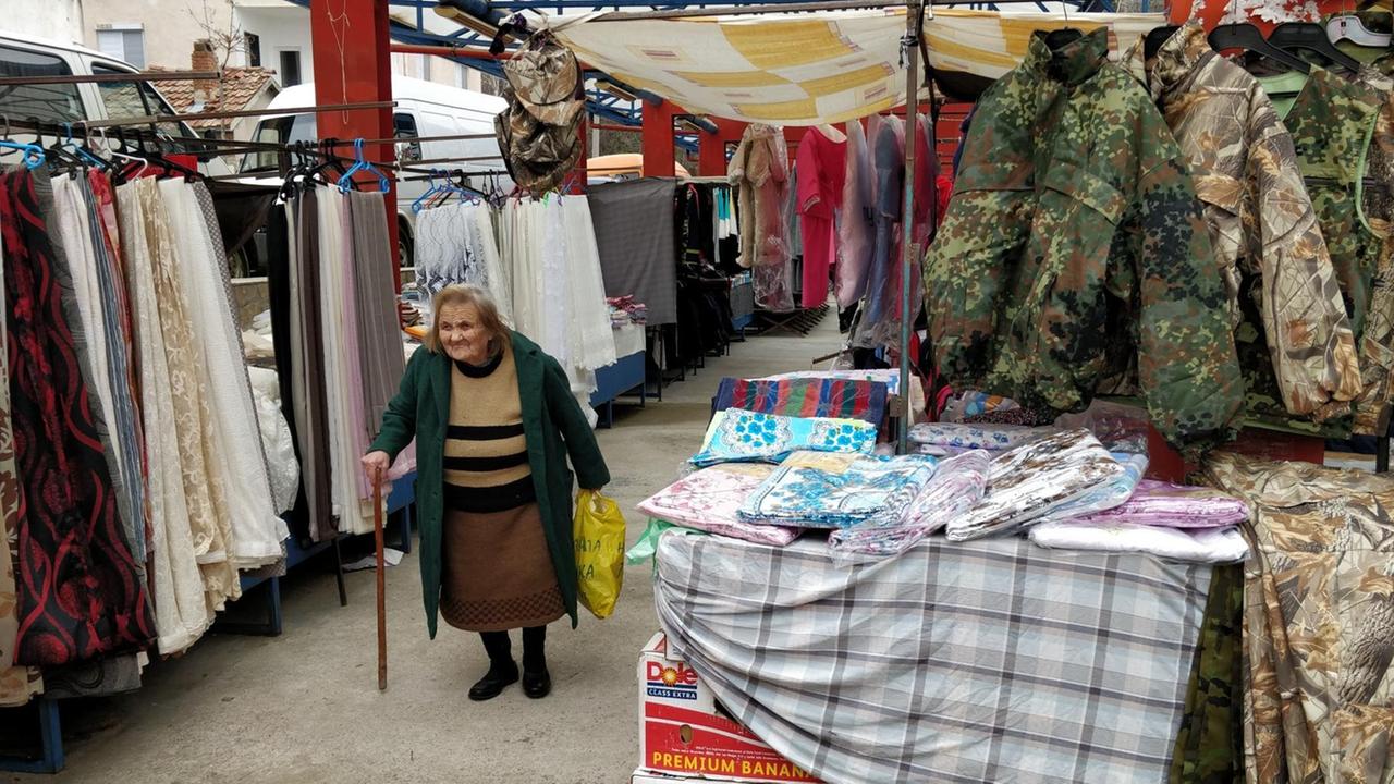 Eine alte Frau geht über den Wochenmarkt von Iwajlowgrad in Bulgarien Eine alte Frau geht über den Wochenmarkt von Iwajlowgrad in Bulgarien