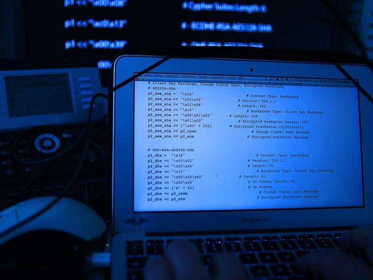 Ein Mann vor einem Rechner mit Quellcode auf dem Bildschirm.