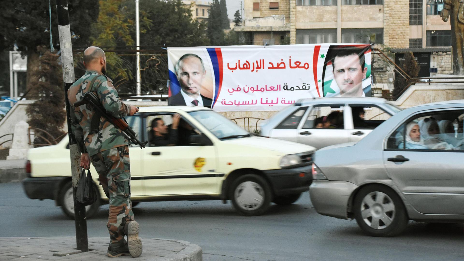 Straßenszene in der nordsyrischen Stadt Aleppo am 17. Oktober 2015, im Hintergrund eine Werbeplakat mit Porträts des russischen Präsidenten Wladimir Putin und seines syrischen Kollegen, Baschar Al-Assad Straßenszene in der nordsyrischen Stadt Aleppo am 17. Oktober 2015, im Hintergrund eine Werbeplakat mit Porträts des russischen Präsidenten Wladimir Putin und seines syrischen Kollegen, Baschar Al-Assad