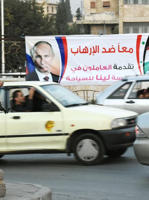 Straßenszene in der nordsyrischen Stadt Aleppo am 17. Oktober 2015, im Hintergrund eine Werbeplakat mit Porträts des russischen Präsidenten Wladimir Putin und seines syrischen Kollegen, Baschar Al-Assad