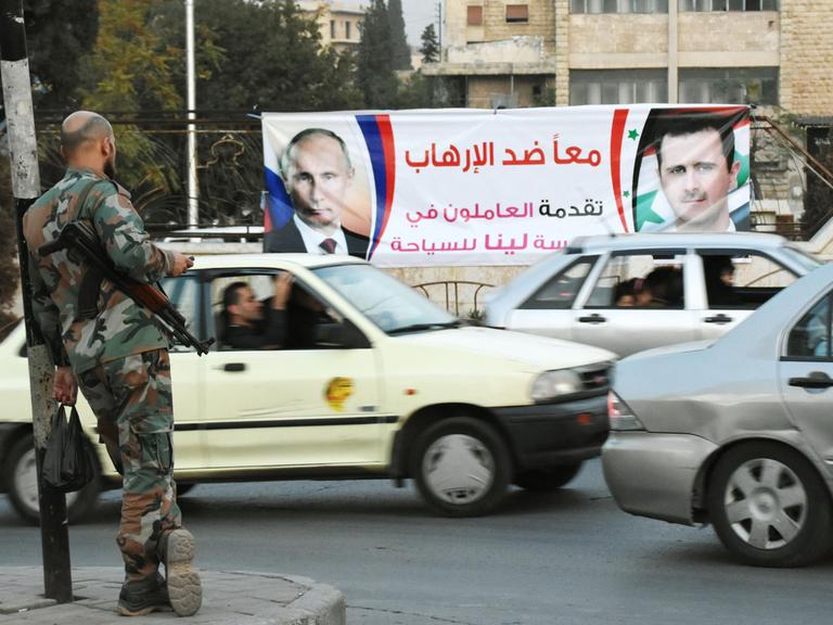 Straßenszene in der nordsyrischen Stadt Aleppo am 17. Oktober 2015, im Hintergrund eine Werbeplakat mit Porträts des russischen Präsidenten Wladimir Putin und seines syrischen Kollegen, Baschar Al-Assad
