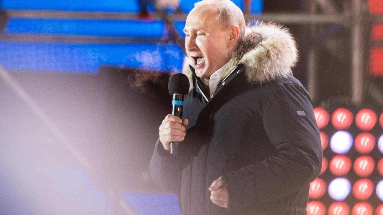 Russlands Präsident spricht auf einer Bühne mit Mikrophon nach gewonnener Wahl zu seinen Anhängern Russlands Präsident spricht auf einer Bühne mit Mikrophon nach gewonnener Wahl zu seinen Anhängern