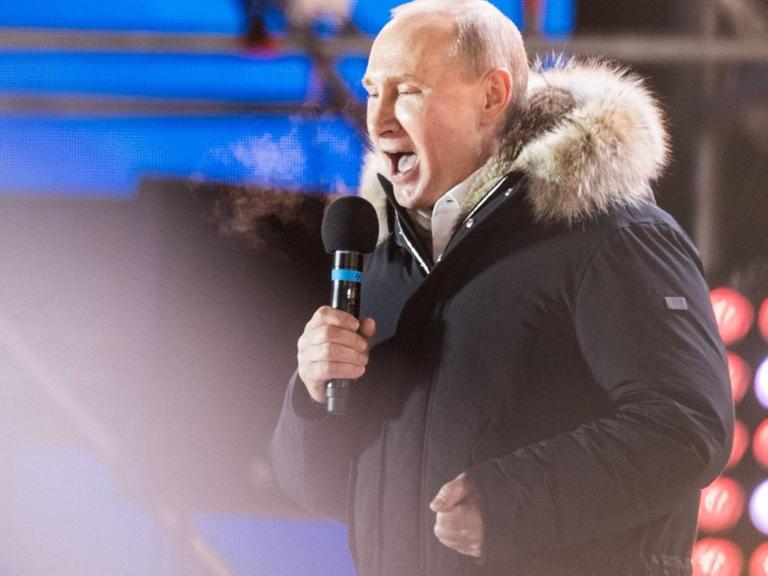 Russlands Präsident spricht auf einer Bühne mit Mikrophon nach gewonnener Wahl zu seinen Anhängern