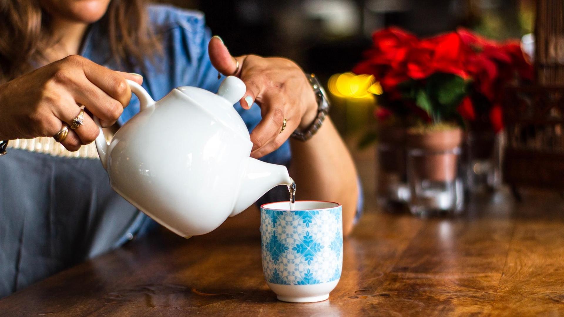 Eine Frau schenkt sich Teewasse in eine Tasse ein. Eine Frau schenkt sich Teewasse in eine Tasse ein.