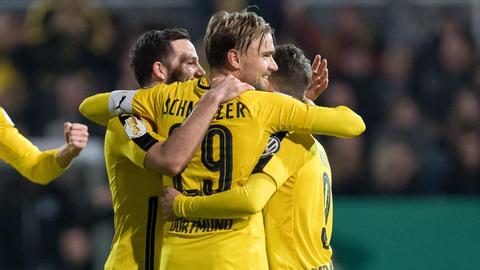 Die drei Spieler halten sich in den Armen, Schmelzer ist von hinten zu sehen und blickt lachend zur Seite, Mors Gesicht ist verdeckt.