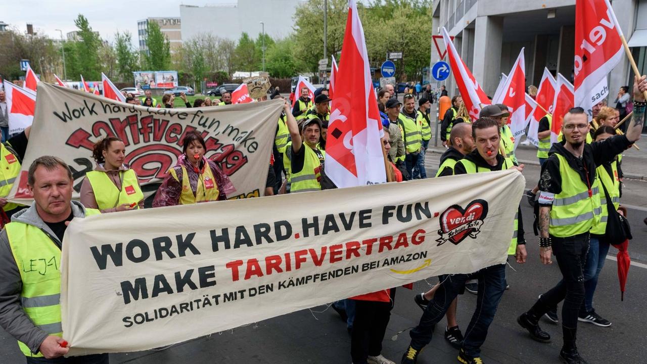 Demonstranten in gelben Westen tragen ein Transparent mit der Aufschrift "Work Hard, Have Fun. Make Tarifvertrag" Demonstranten in gelben Westen tragen ein Transparent mit der Aufschrift "Work Hard, Have Fun. Make Tarifvertrag"