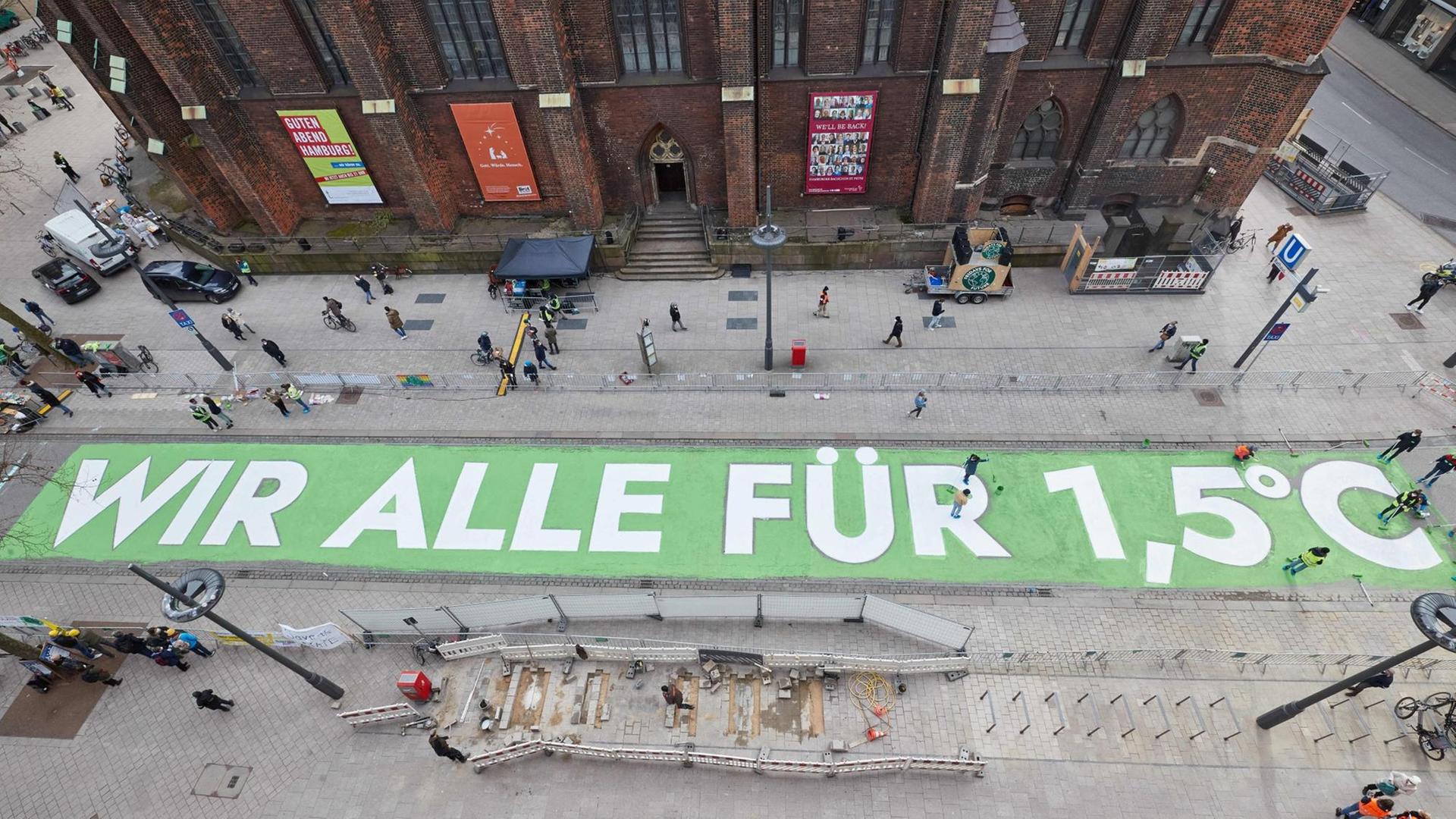 Aktivisten von "Fridays for Future" malen den Schriftzug "Wir alle für 1,5 Grad" auf die Mönckebergstraße in Hamburg. Aktivisten von "Fridays for Future" malen den Schriftzug "Wir alle für 1,5 Grad" auf die Mönckebergstraße in Hamburg.