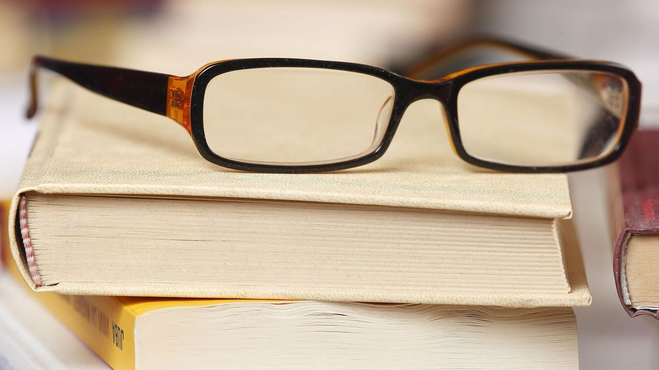 Eine Lesebrille liegt auf einem Bücherstapel. Eine Lesebrille liegt auf einem Bücherstapel.