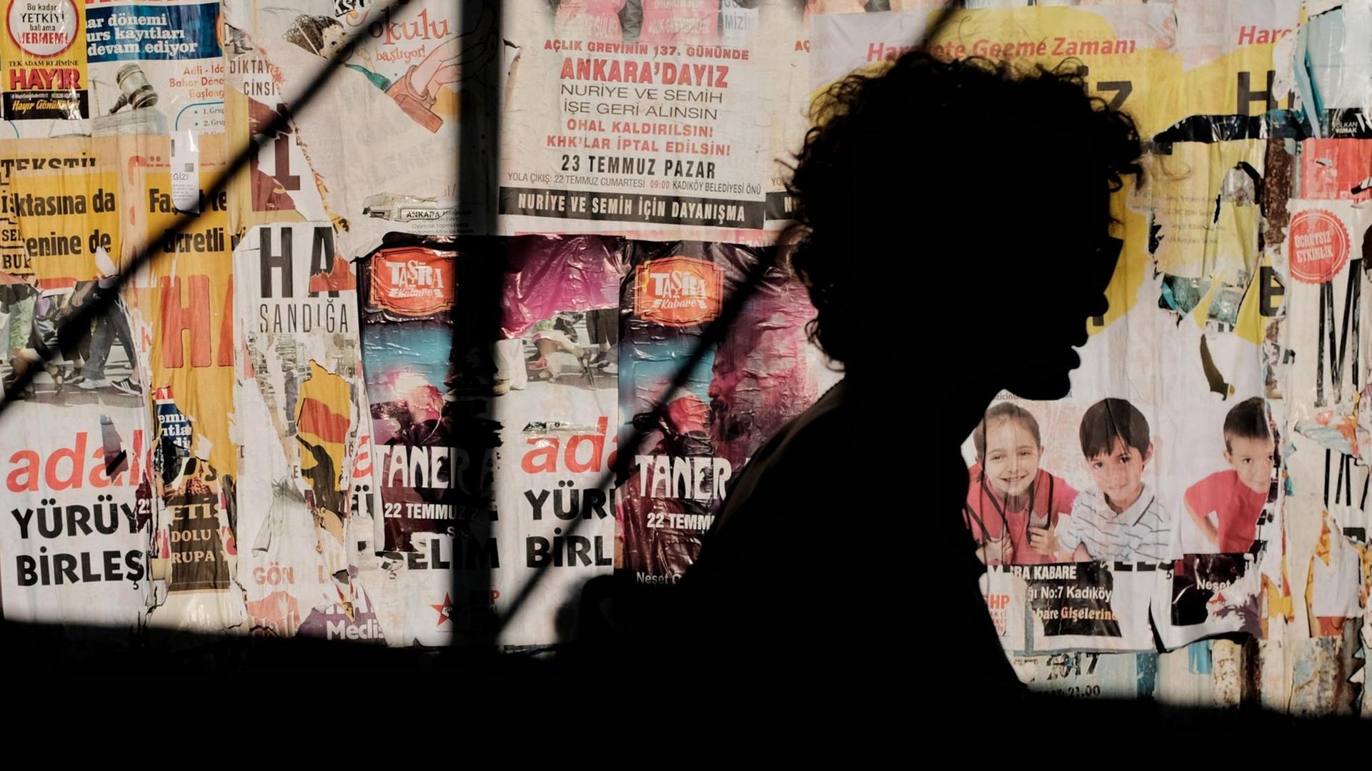 Silhouette eine Person vor einer Wand mit türkischen Postern. Silhouette eine Person vor einer Wand mit türkischen Postern.