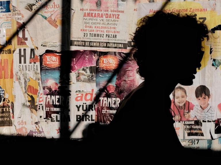 Silhouette eine Person vor einer Wand mit türkischen Postern.