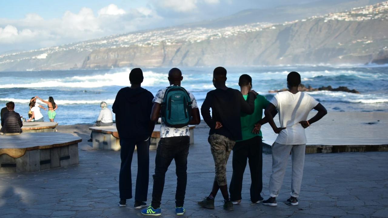 Fünf junge Schwarzafrikaner stehen mit dem Rücken zur Kamera an der Küste und schauen ins Meer. Fünf junge Schwarzafrikaner stehen mit dem Rücken zur Kamera an der Küste und schauen ins Meer.