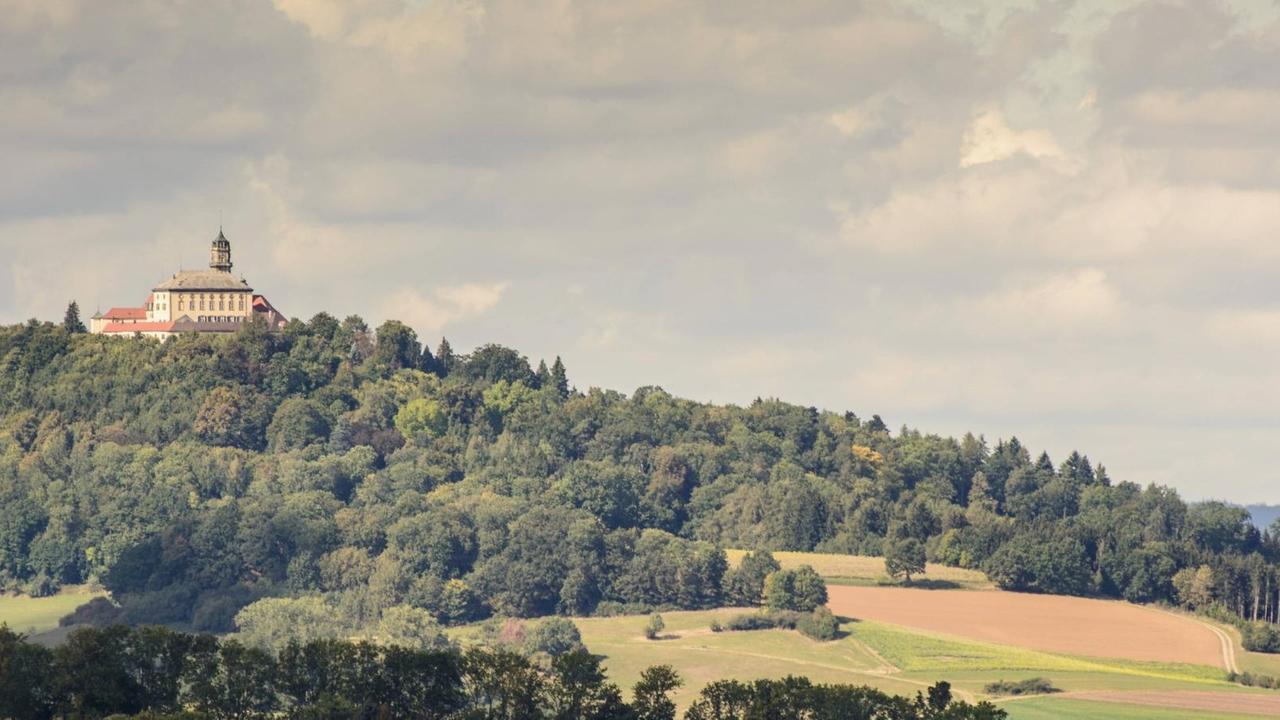 Auf einem bewaldeten Hügel zeigt sich die barocke Schlossanlage. Auf einem bewaldeten Hügel zeigt sich die barocke Schlossanlage.