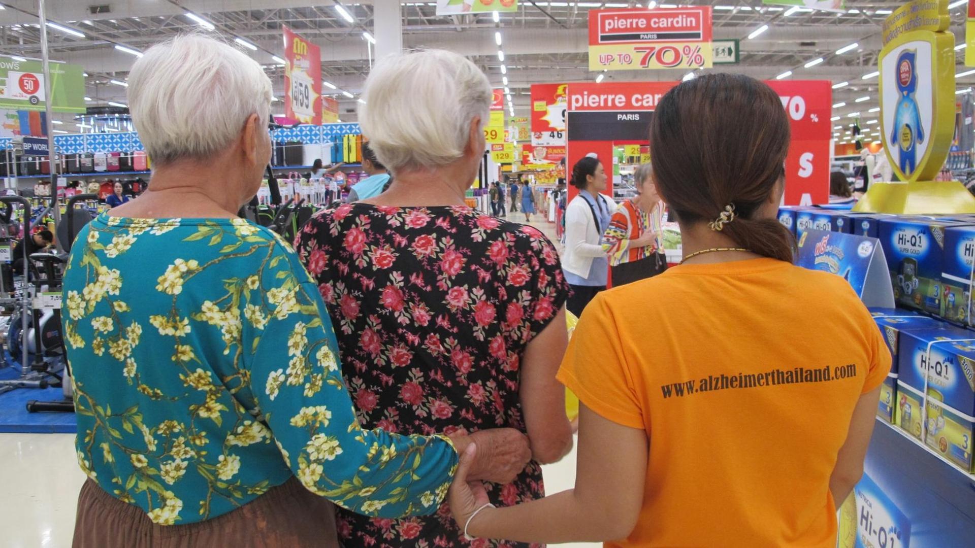 Betreuerin Tay (r), aufgenommen am 09.09.2016 in der Nähe von Chiang Mai in Nordthailand) mit zwei demenzkranken Gästen bei einem Shopping-Ausflug. Im Dorf Faham, 20 Kilometer nördlich von Chiang Mai gibt es eine Einrichtung «Baan Kamlangchay» für gut ein Dutzend Langzeitgäste in verschiedenen Demenzstadien, die von mehr als 40 Mitarbeitern betreut werden. Betreuerin Tay (r), aufgenommen am 09.09.2016 in der Nähe von Chiang Mai in Nordthailand) mit zwei demenzkranken Gästen bei einem Shopping-Ausflug. Im Dorf Faham, 20 Kilometer nördlich von Chiang Mai gibt es eine Einrichtung «Baan Kamlangchay» für gut ein Dutzend Langzeitgäste in verschiedenen Demenzstadien, die von mehr als 40 Mitarbeitern betreut werden.