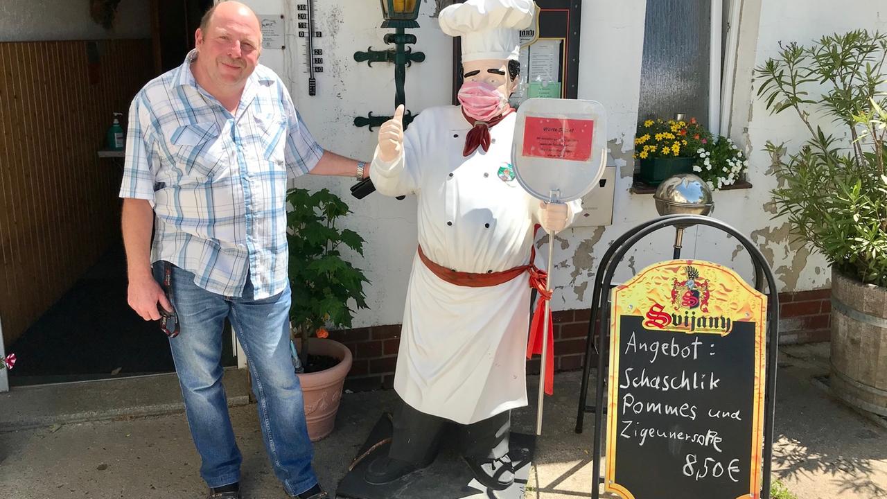 Knut Popken steht am Eingang seiner Gaststätte. Neben ihm wirbt eine Tafel für Schaschlik mit Pommes. Knut Popken steht am Eingang seiner Gaststätte. Neben ihm wirbt eine Tafel für Schaschlik mit Pommes.