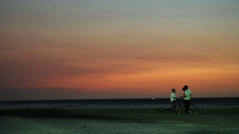 Drei junge Männer stehen bei Sonnenuntergang an der kolumbianischen Karibikküste